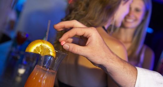 Man's hand drugging woman's drink