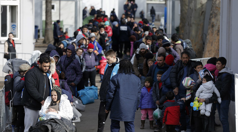Migrants and refugees queue to board a train in the town of Sid, Serbia