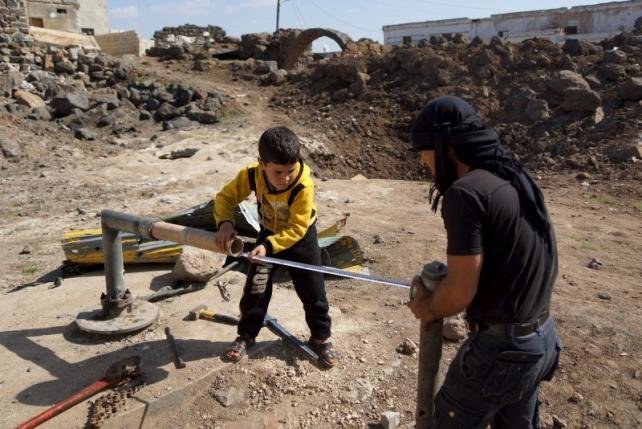  Civilians fix damaged water pipes in the rebel held al-Ghariyah al-Gharbiyah town, in Deraa province