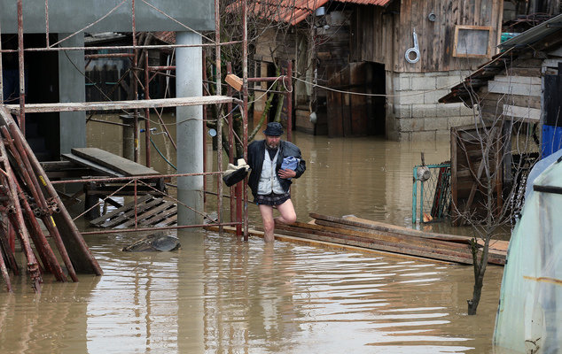A man walks in front of a his flooded home in Pozega, some 150 kilometers south of Belgrade, Serbia, Monday, March 7, 2016.