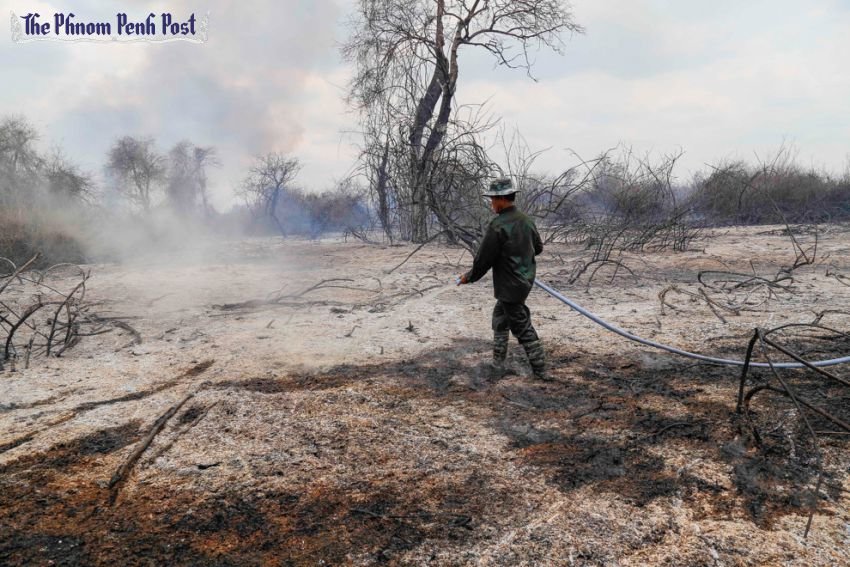 A man hoses down smouldering patches of scorched earth in Battambang province after a fire ripped through a flooded forest. 