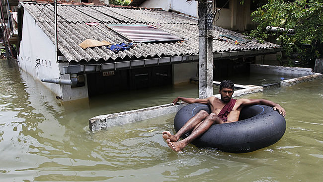 A Sri Lankan man uses an inflatable tube to move through a flood-affected area in Wellampitiya, outskirts of Colombo, Sri Lanka, Friday, May 20, 2016.