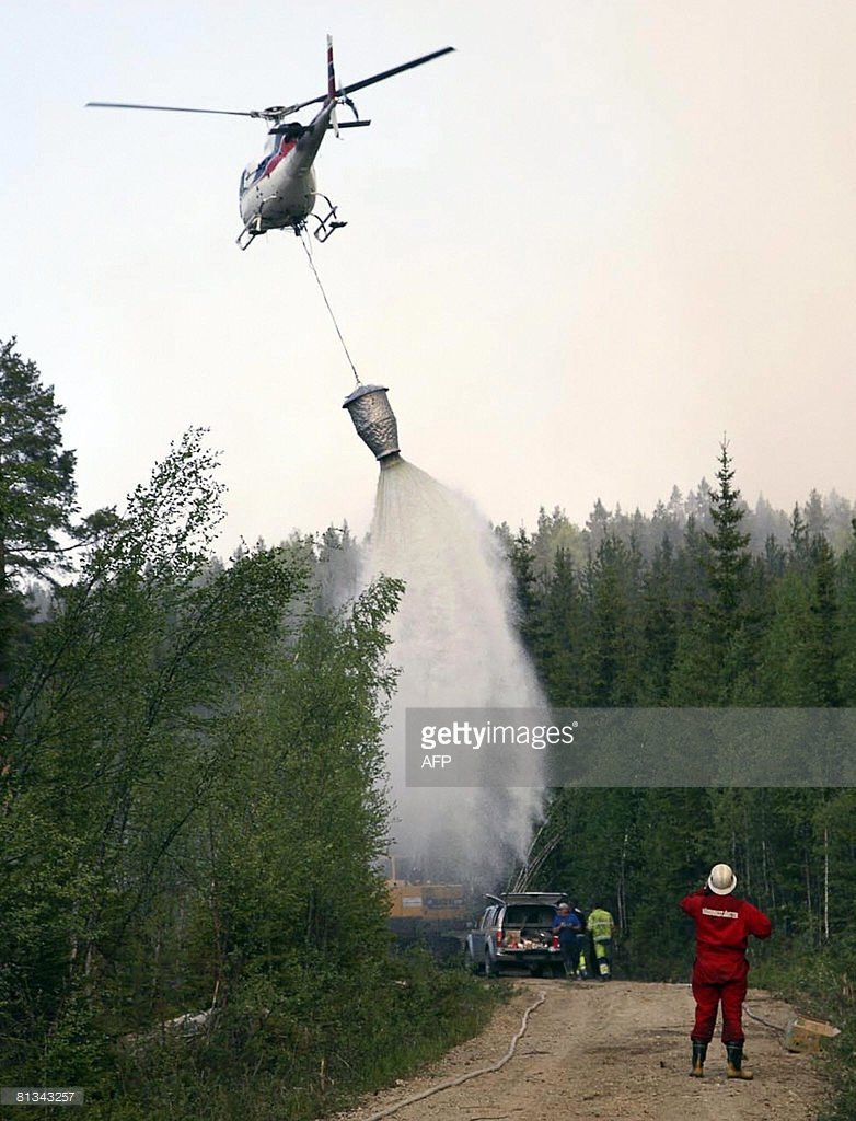 A helicopter drops water on the wildfire