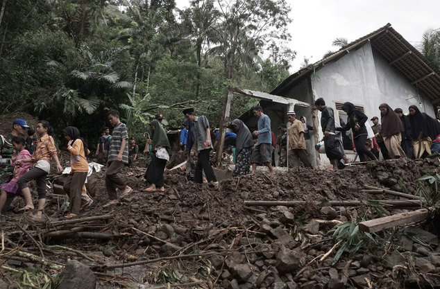 Villagers walk through the area affected by landslides in Banjarnegara, Central Java, Indonesia. Sunday, June 19, 2016. An Indonesian official said dozens of people have been killed by flooding and landslides in central Java and many others remain missing