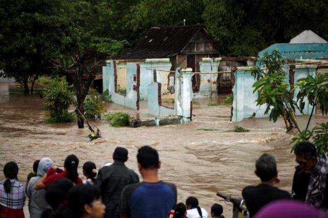  People stand in front of a flooded area in Kampung Sewuresidential area in Solo, Central Java province, Indonesia, June 19, 2016. 
