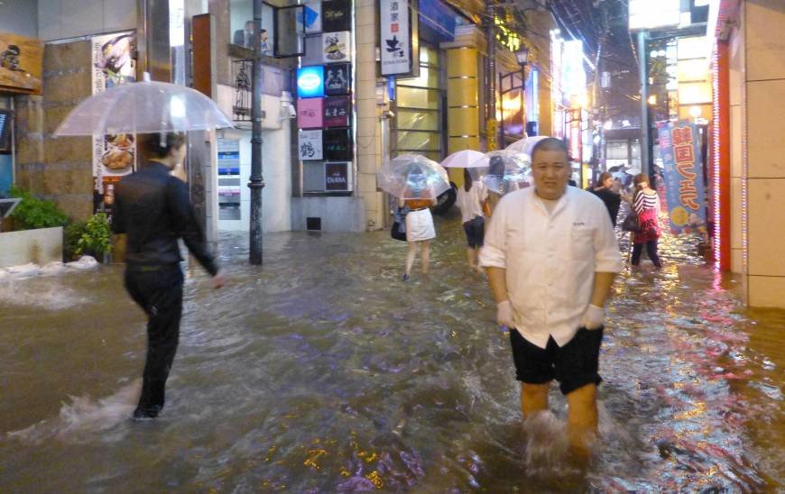 People walk on the streets of Nagasaki Monday night as torrential rain flooded wide parts of the prefecture and elsewhere in Kyushu. 