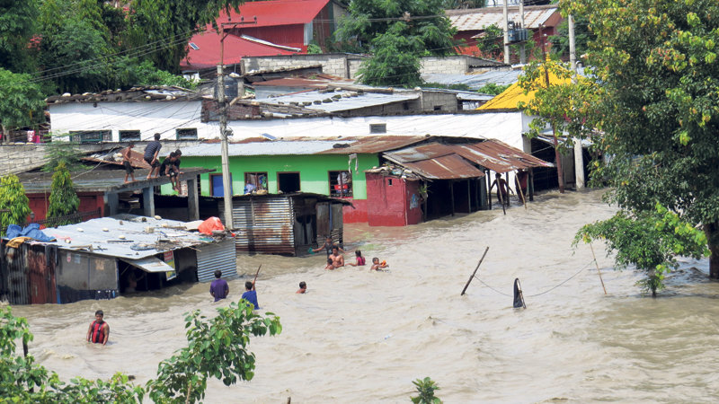 Men, women and children at a squatter settlement in Gaidakot, Nawalparasi wade through floodwaters from the Narayani River that inundated their homes Tuesday. The water level in the river reached 10.24 meters in the evening. 