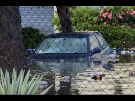 A car sits in high water in the parking lot of the Wallenford Coffee Company in St Andrew yesterday.