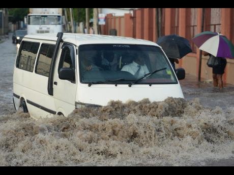 A motorist navigates a flooded roadway at the intersection of East Ave in Greenwich Farm and Marcus Garvey Drive in St Andrew yesterday.