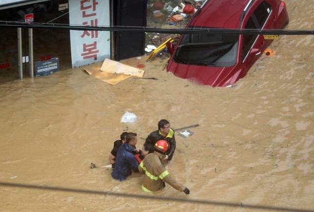 Rescue workers carry a resident through a flooded street caused by Typhoon Chaba in Ulsan