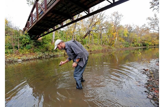 Anthony Sasson, freshwater conservation manager for the Nature Conservancy in Ohio, picks up a dead mussel in the Big Darby Creek at Prairie Oaks Metro Park.