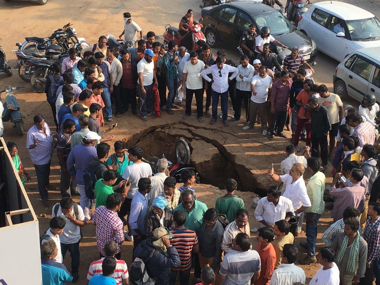 Bystanders gather round to watch after two motorcycles fell into a sink hole after a road caved in at Safilguda, a suburb of Hyderabad. 
