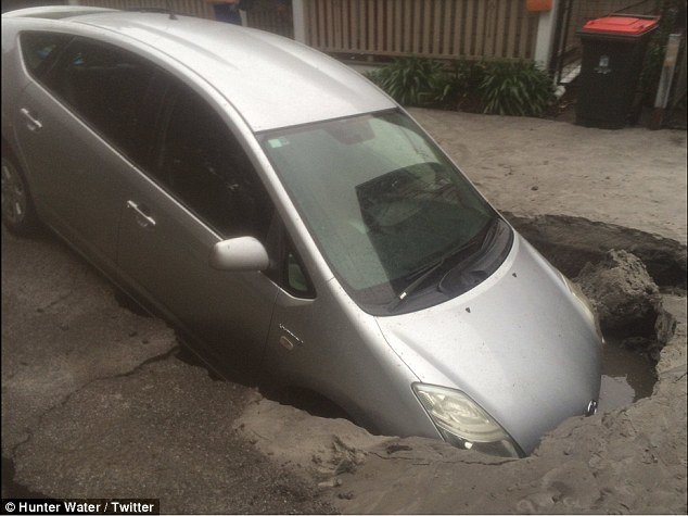 The front part of a car has been completely swallowed up by a one-metre deep sinkhole after a water main break