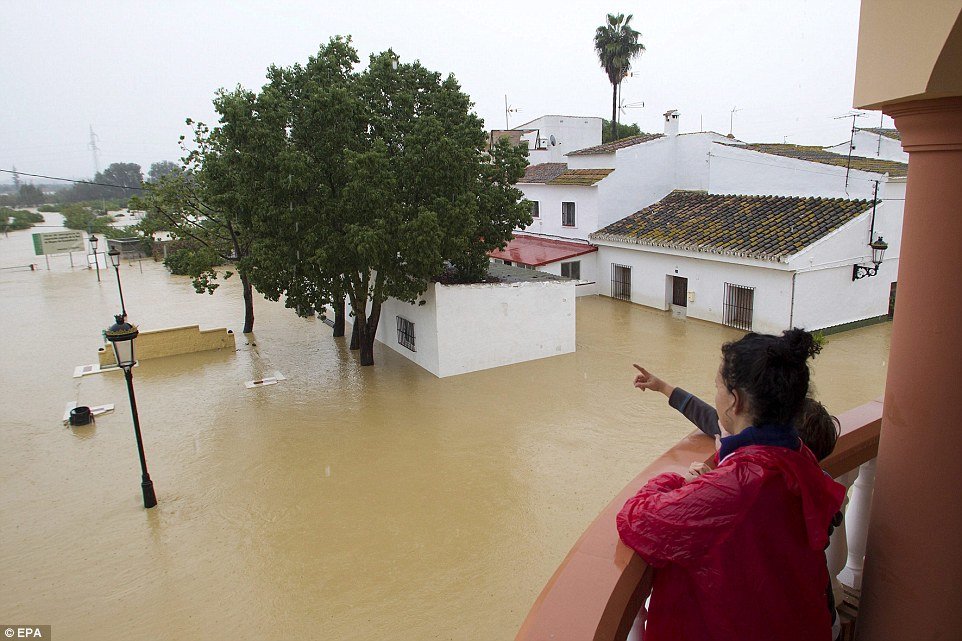 A woman and a young child look out from their balcony at the street below which is buried under floodwaters. Police in Spain said this is worst flood for nearly 30 years