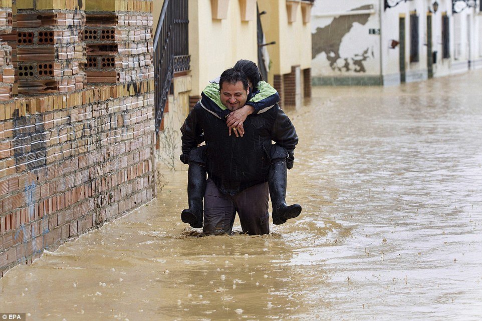 A resident carries a woman on his back through a street in Dona Ana which resembles a river as heavy rains fall on the town