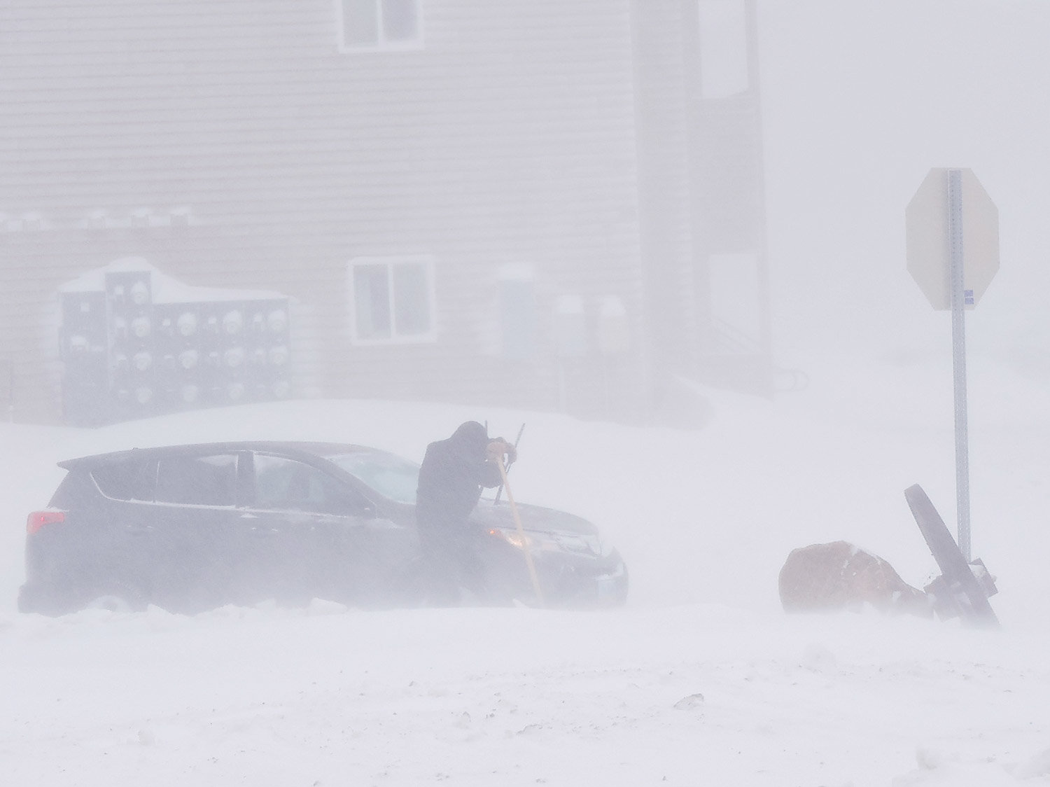  An exhausted man takes a break from the task of attempting to shovel his vehicle out of deep snow at a northwest Minot intersection Tuesday morning