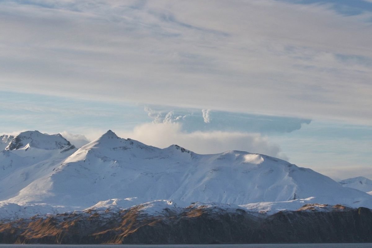 A plume rises from Bogoslof volcano, partially obscured by a mountain on Unalaska Island, in this view from Unalaska, about 60 miles east of the volcano, on Wednesday, Dec. 22, 2016.