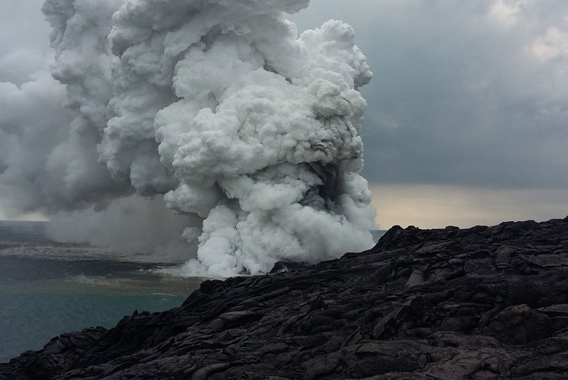 A large plume of rock debris and gas emanates from the Kamokuna lava ocean entry within Hawaii Volcanoes National Park, just moments after the lava delta began to collapse.