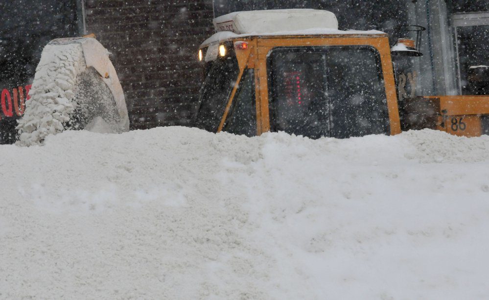 A Waterville Public Works department employee struggles to clear the sidewalk of snow along Elm Street in Waterville during the storm on Monday. 