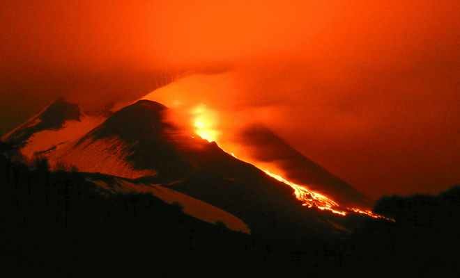 Italy's Mount Etna glows as lava pours down its flanks