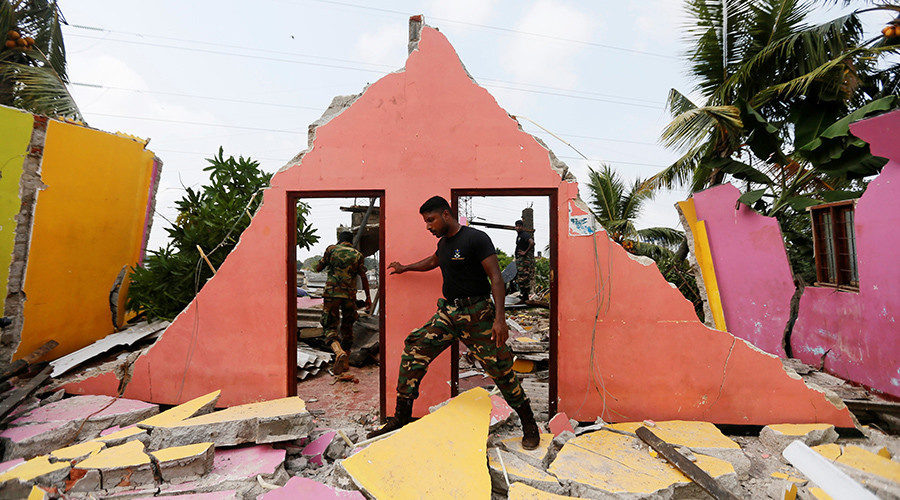 A member of the military inspects a damaged house for victims during a rescue mission after a garabage dump collapsed and buried dozens of houses in Colombo