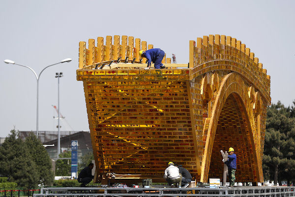 Workers install wires on a 'Golden Bridge of Silk Road'