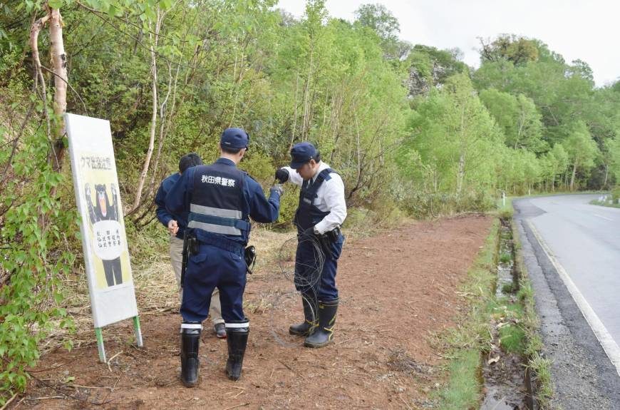 Police officers put up a no-entry sign at the foot of the mountains in the city of Senboku, Akita Prefecture, on Saturday.