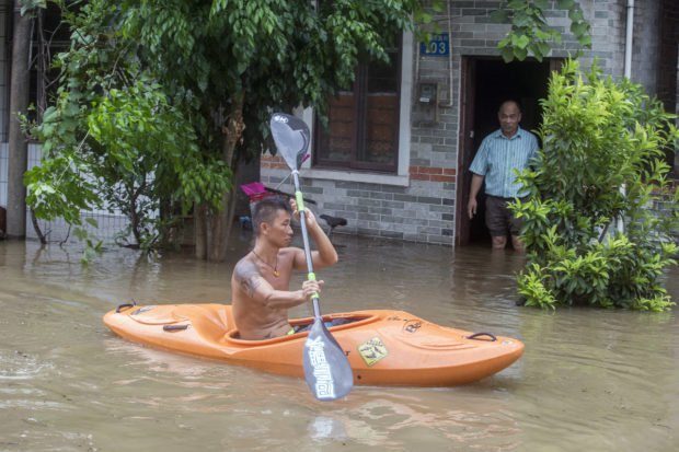 A man paddles a kayak along a flooded street caused by Typhoon Hato in Guangzhou in southern China's Guangdong province Wednesday Aug. 23, 2017