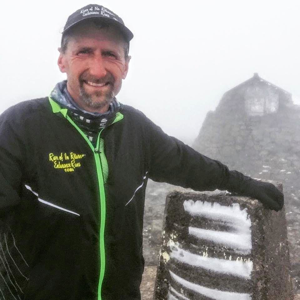 Running coach Paul Lind poses next to first snow on Ben Nevis