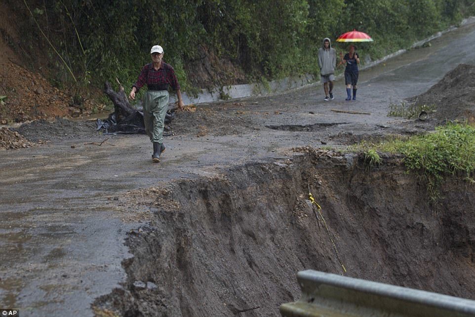 Tropical Storm Nate unleashed intense rainfall across much of Central America on Thursday, killing at least eight people in Costa Rica. Locals near San Jose, Costa Rica, are seen above walking past a washed out road on Thursday