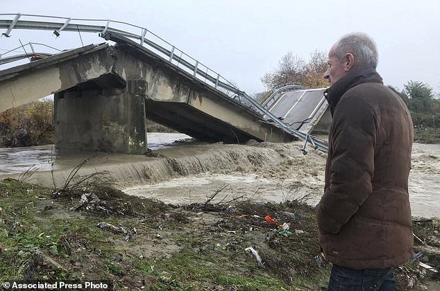 Local resident Nue Shkreta looks at a collapsed bridge at the entrance of his village Mamuras, northern Albania, Friday, Dec. 1, 2017.