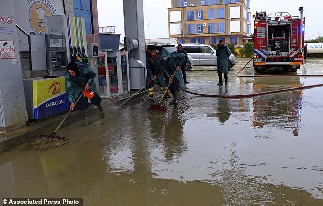 Workers remove water from a gas station after heavy rainfalls in Tirana, Friday, Dec. 1, 2017.
