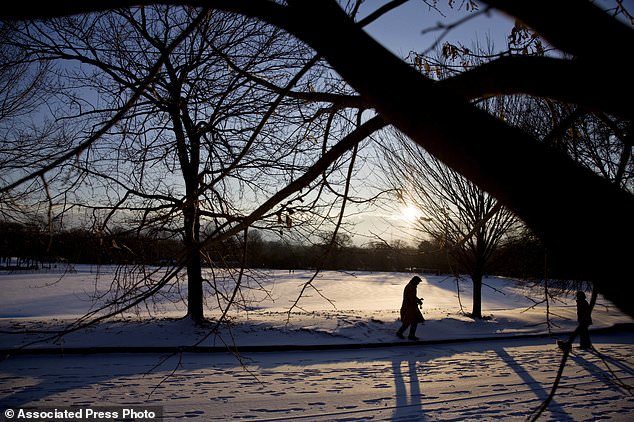 A person walks through a snow covered Piedmont Park as the sun rises in Atlanta, Wednesday, Jan. 17, 2018.