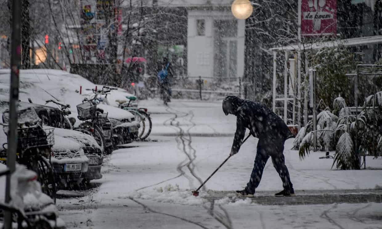 A woman clears snow from the pavement in Hamburg, northern Germany.