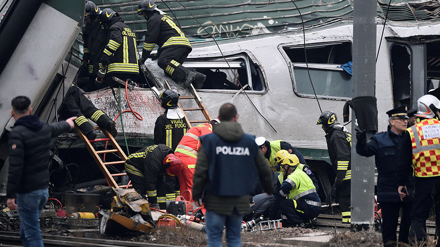Fire fighters and police officers work around derailed trains in Pioltello
