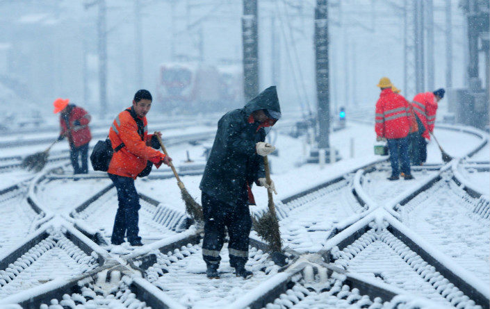 Employees of the Nanchang Railway Bureau, in Jiangxi province, clean snow from the tracks on Jan. 25, 2018.