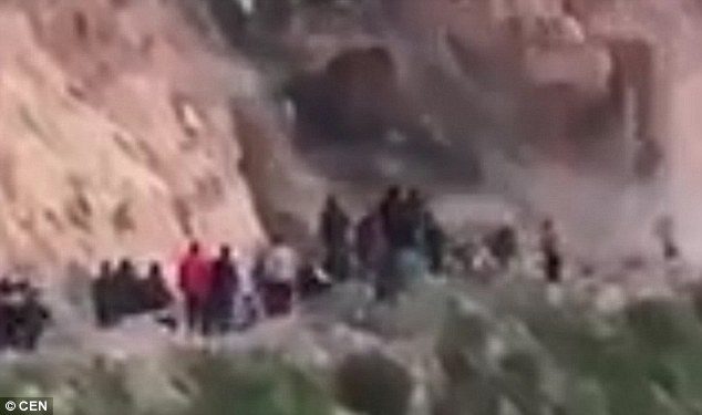 In the footage, hundreds of people are gathered on a mountain road after earlier landslides made it hard to cross
