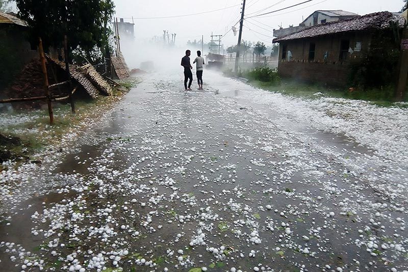 Two men stand on the road to see the hailstones fallen in Pipara area of Durga Bhagawati Rural Municipality, in Rautahat district, on Friday, March 30, 2018.
