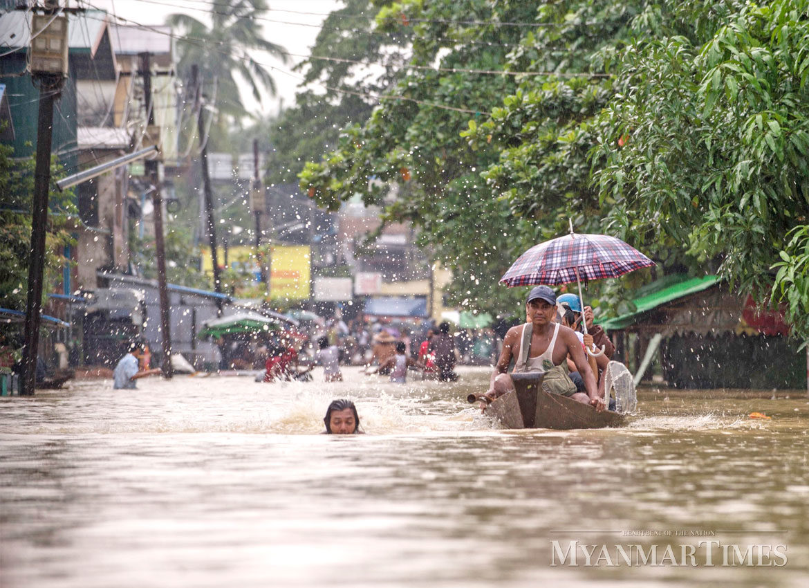 Residents make their way through flooded streets in Bago Region.