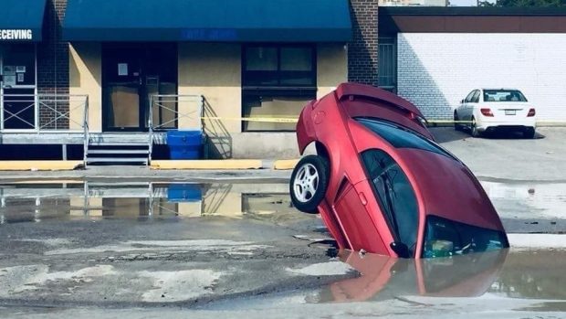 A car was partly swallowed by a sinkhole caused by a watermain break in Toronto's Weston neighbourhood on Aug. 7, 2018.