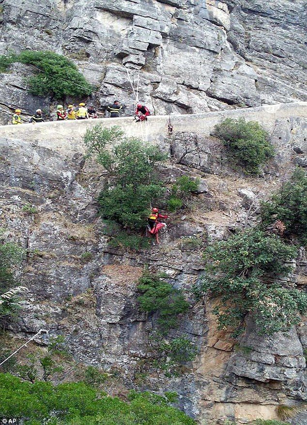 Rescuers work at the Raganello Gorge in Civita, Italy today: TV images show rescuers scaling down the side of a steep rock face to bring hikers to safety