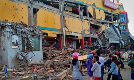 Residents outside a badly damaged shopping mall following Friday's tsunami in Palu