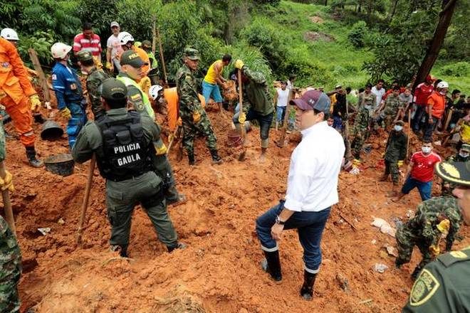 Governor of Santander Didier Tavera (centre), stands next to rescue workers as they work at the area where nine people died by mudslides caused by heavy rains, according to local authorities, in Barrancabermeja, Colombia on Sunday.