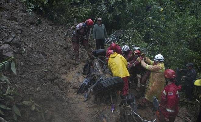 Firefighters try to rescue victims from a car after a mudslide on the outskirts of El Choro, Bolivia, on Saturday, Feb. 2, 2019.