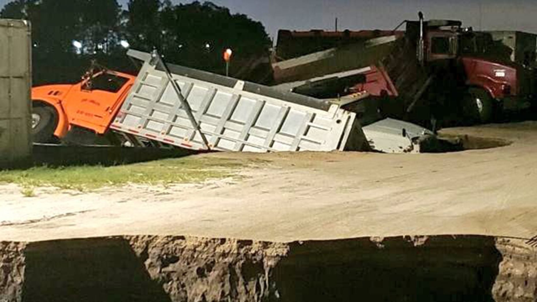 Click to enlarge Trucks can be seen sticking out of a possible sinkhole in Florida early Wednesday.
