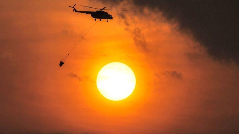 A military helicopter carries water during a fire-monitoring mission over South Sumatra