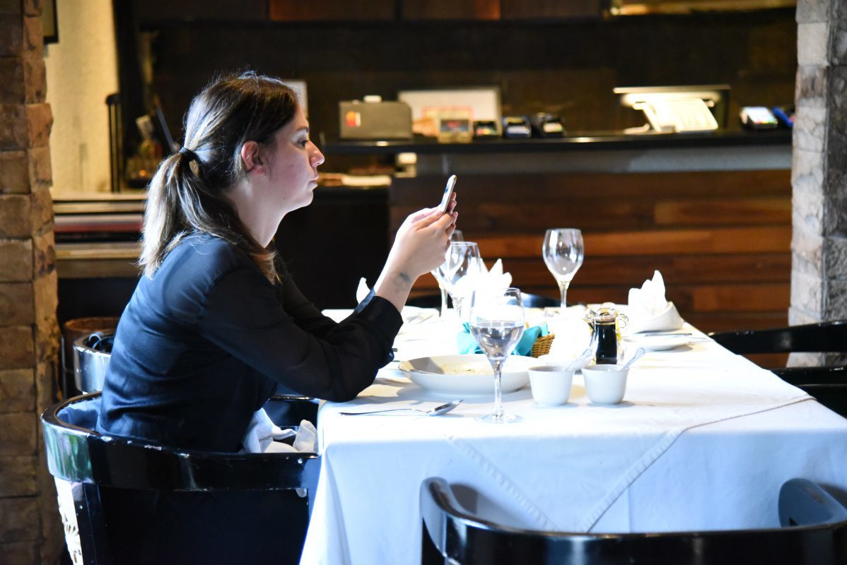 woman dining alone texting phone