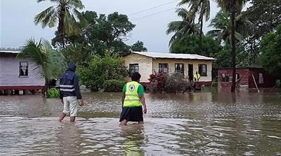Rescue workers make their way through a village during flooding caused by the Tropical Cyclone Harold in Nasolo in Fiji
