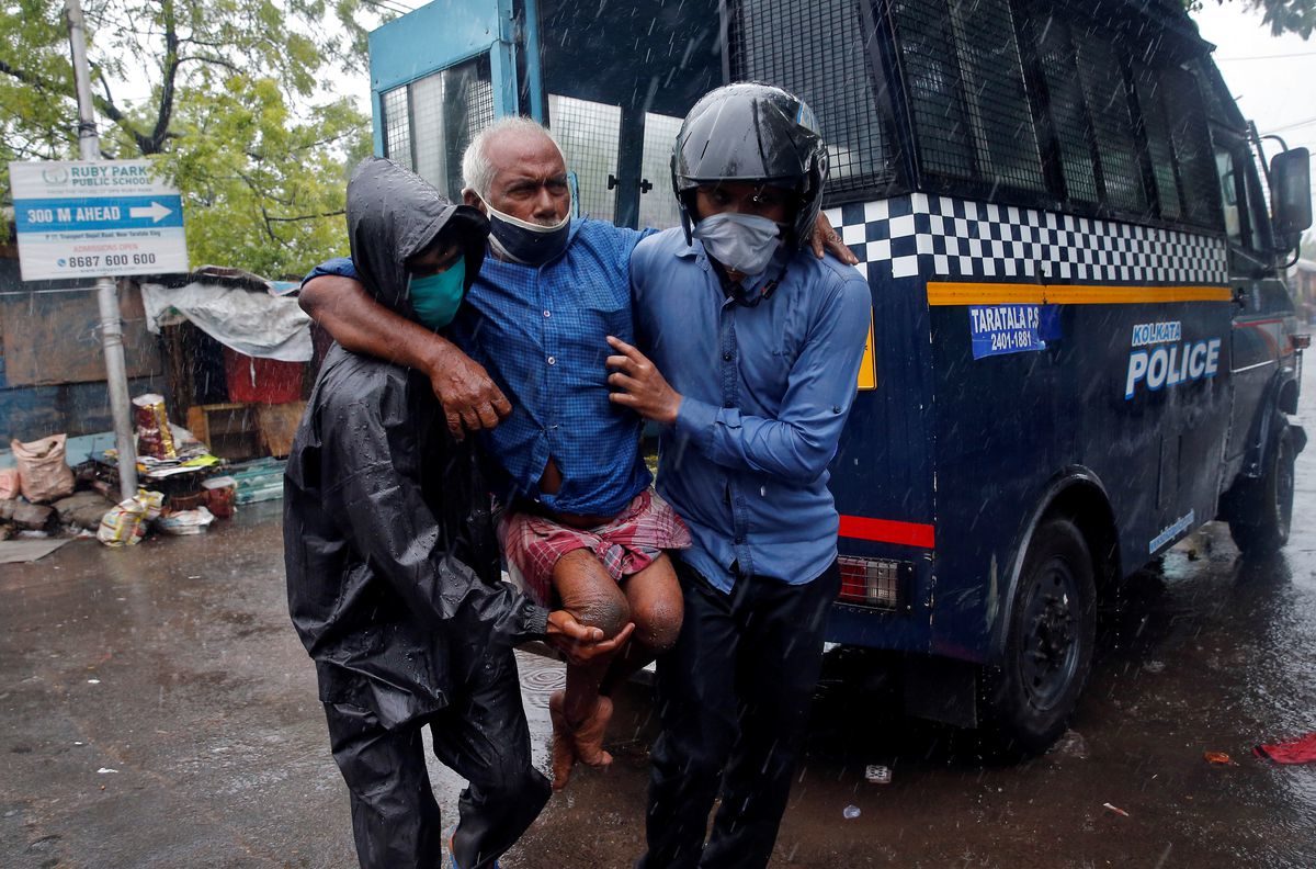 Police officers carry a disabled man to a safer place following his evacuation from a slum area before Cyclone Amphan makes its landfall, in Kolkata, India, on May 20, 2020.