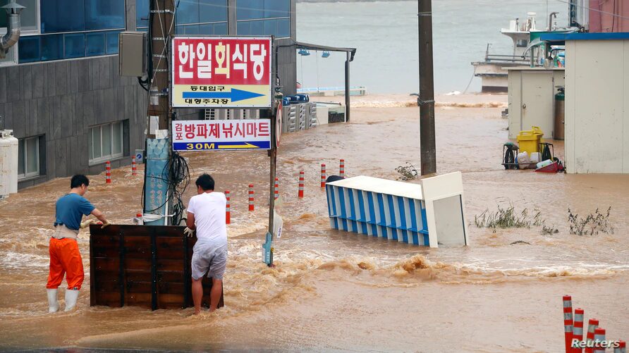 Men stand on a street submerged by typhoon Haishen in Gyeongju